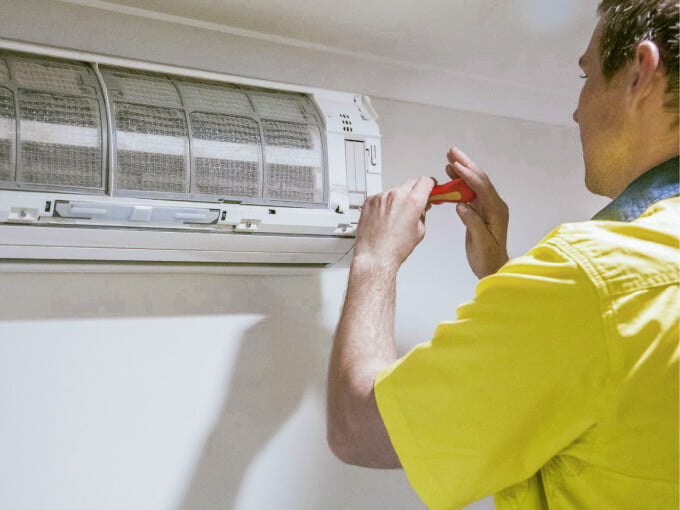 A technician repairing an air conditioner on the Sunshine Coast.