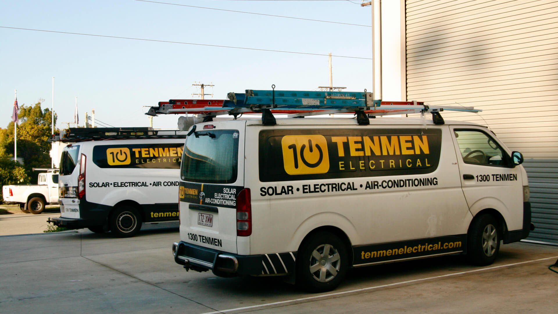 Two Tenmen Electrical vans loaded with air conditioning supply and parked in front of a building on the Sunshine Coast
