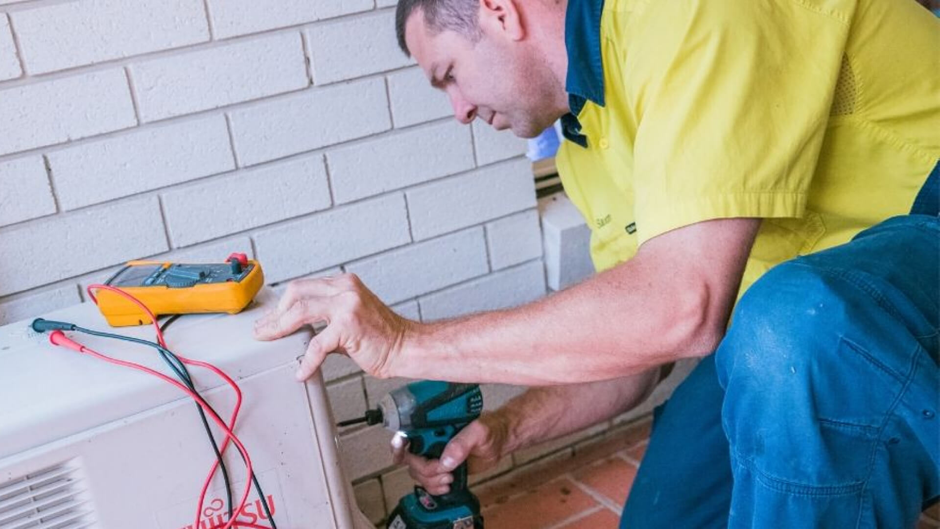 A man is performing air conditioning repair on the Sunshine Coast.