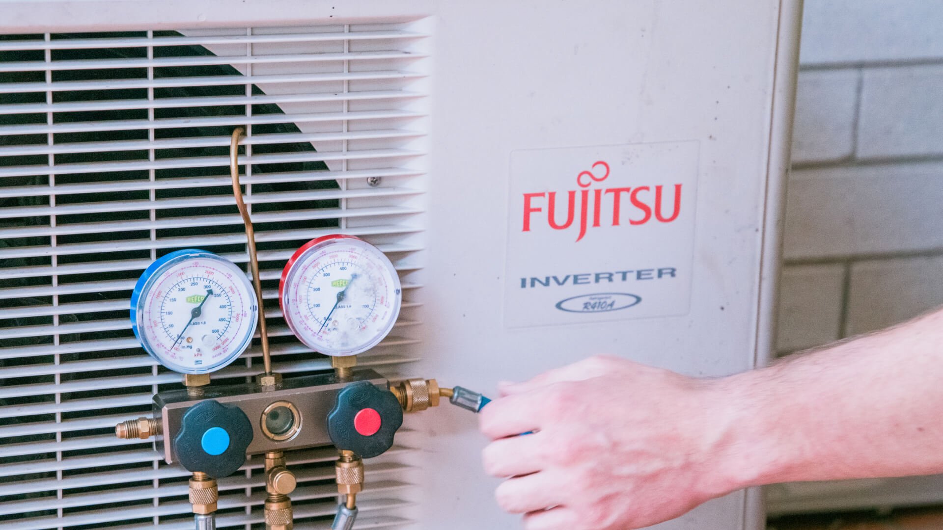 The hand of a technician servicing a Fujitsu air conditioning on the Sunshine Coast.