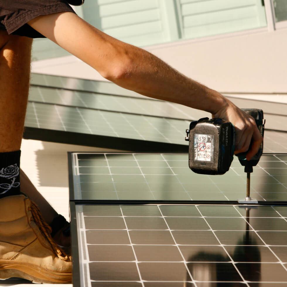 An experienced technician performing solar installation on the Sunshine Coast using a drill.