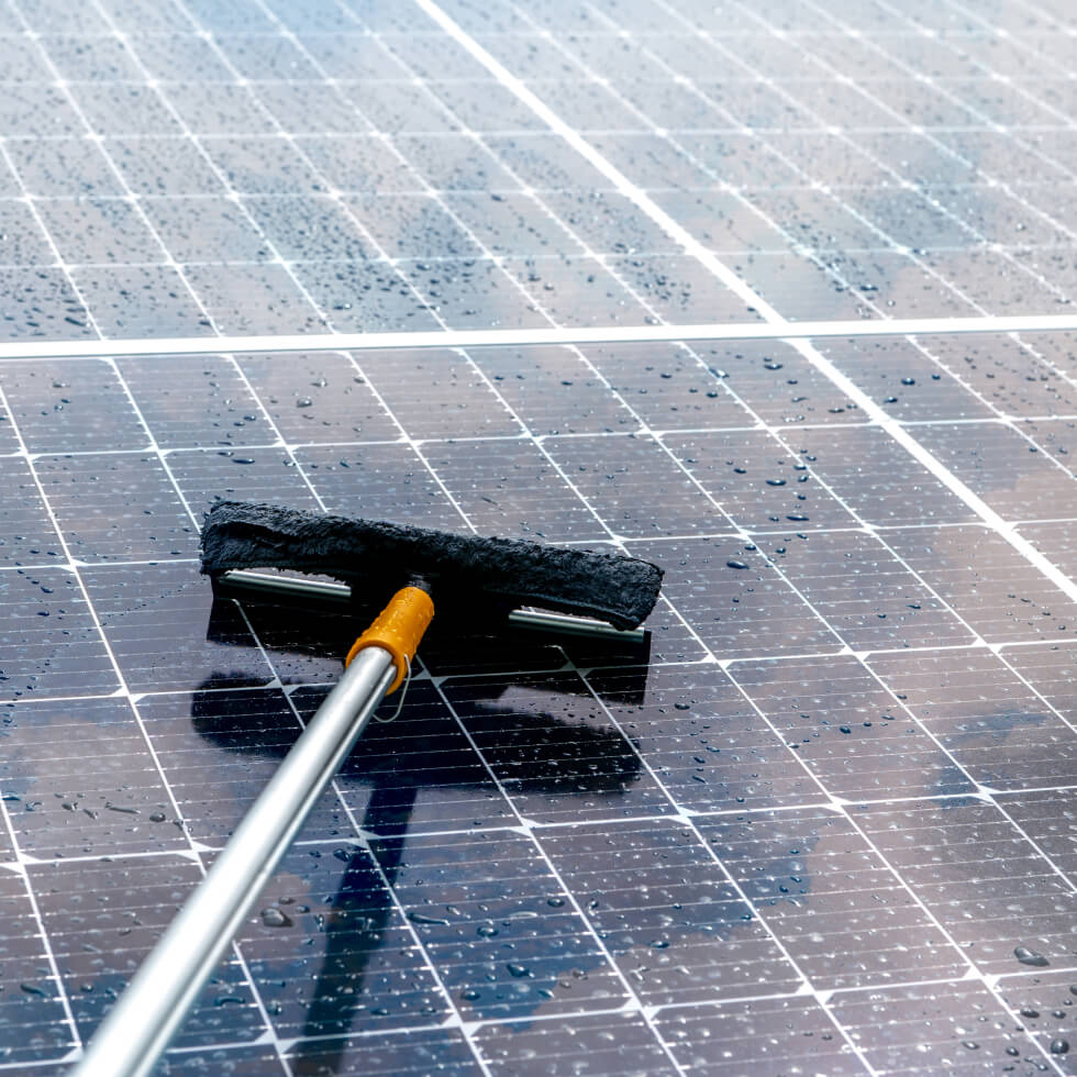 Cleaning solar panels on the Sunshine Coast with a broom.