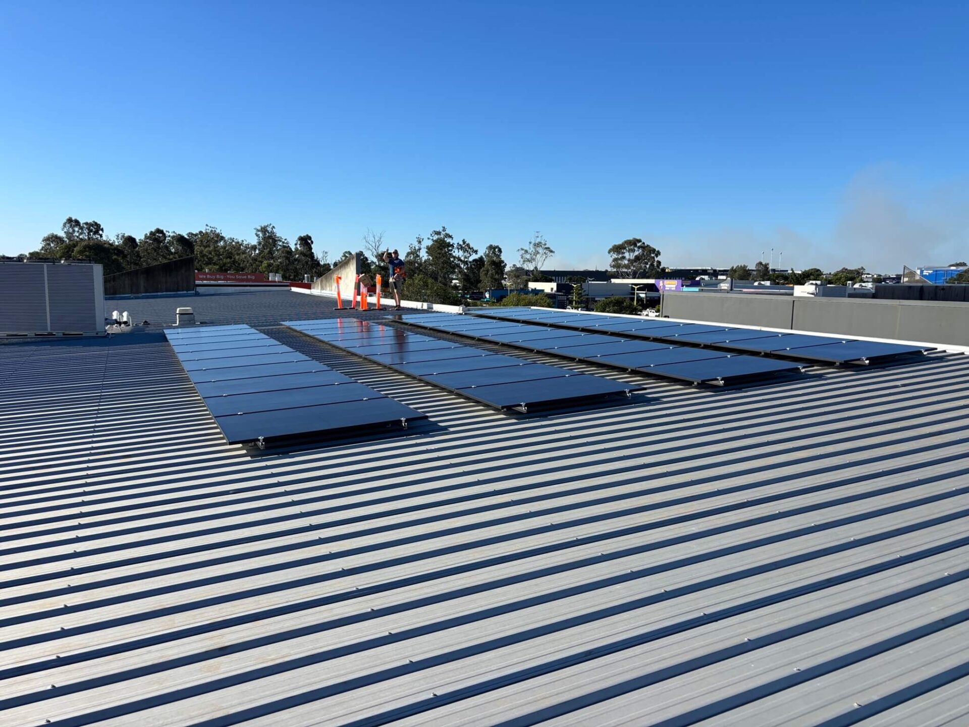 Rows of solar panels installed on a metal roof under a clear blue sky.