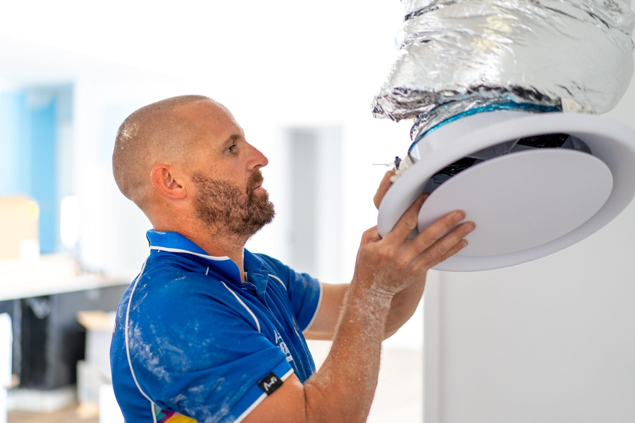 Tenmen Electrical technician installing a ducted air conditioning ceiling diffuser in a Sunshine Coast home.