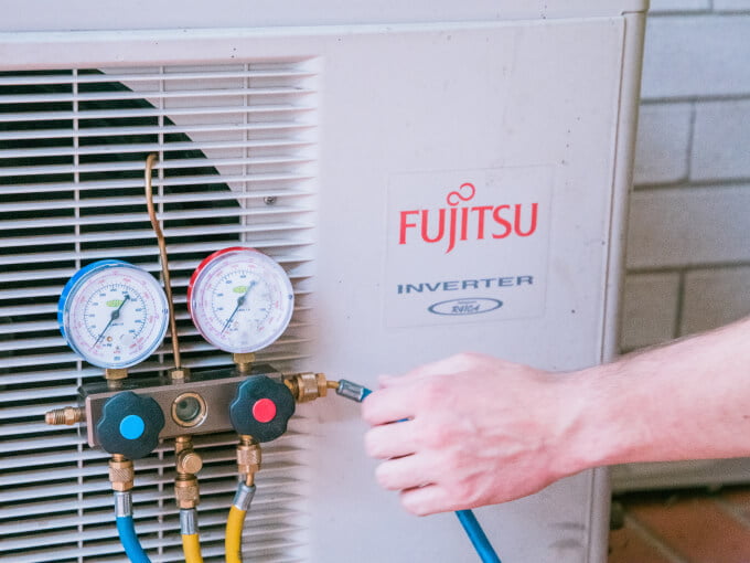 A hand of a technician working on a Fujitsu air conditioner on the Sunshine Coast.