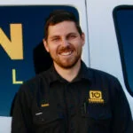 A man in a black shirt standing in front of a van.