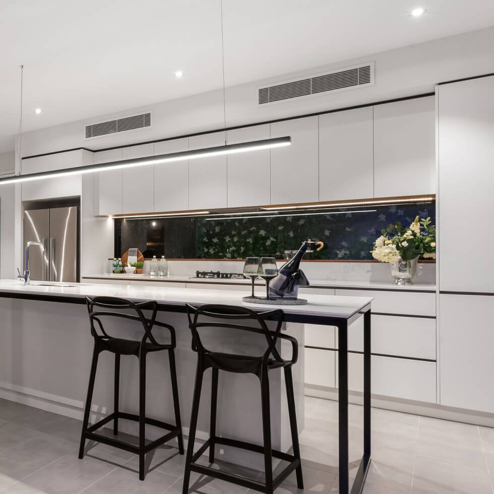A modern kitchen with white cabinets and bar stools, equipped with air conditioning for the ultimate comfort.