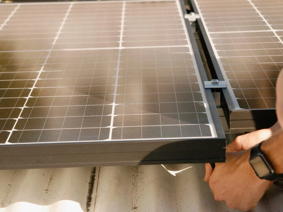 A man fixing a solar panel on a roof.