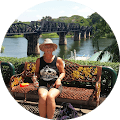 A woman sitting on a bench next to a river.