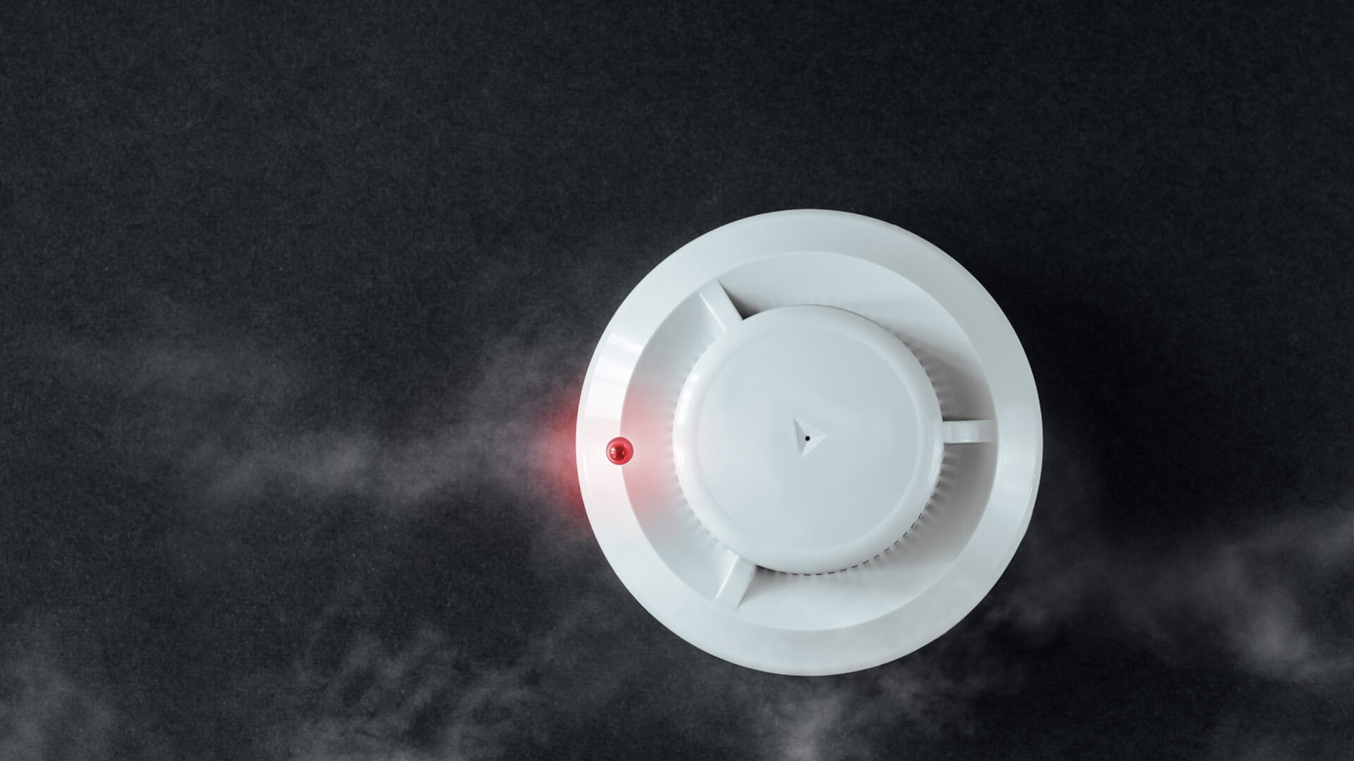A smoke alarm on a black background, being tested on the Sunshine Coast.