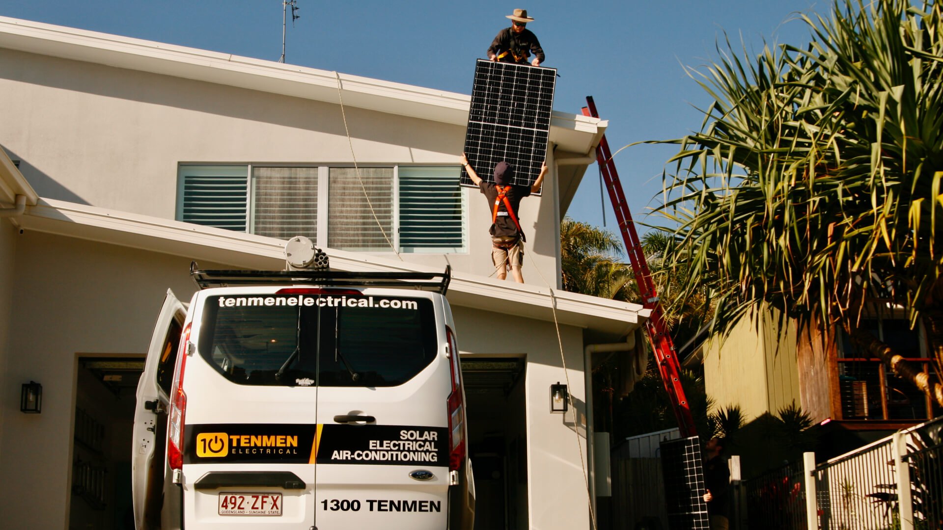 Two solar installers working on a roof of a house in Coolum