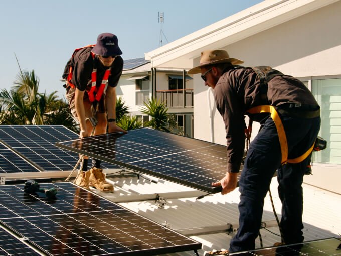 Two men installing solar panels on a roof on the Sunshine Coast