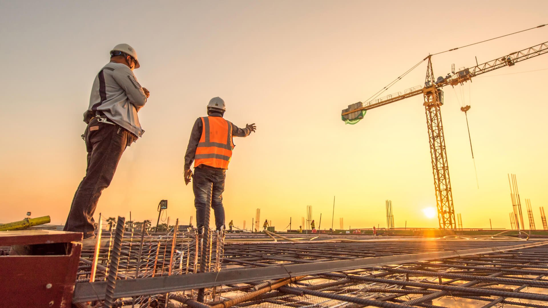 Two construction workers standing on a solar-powered construction site at sunset.