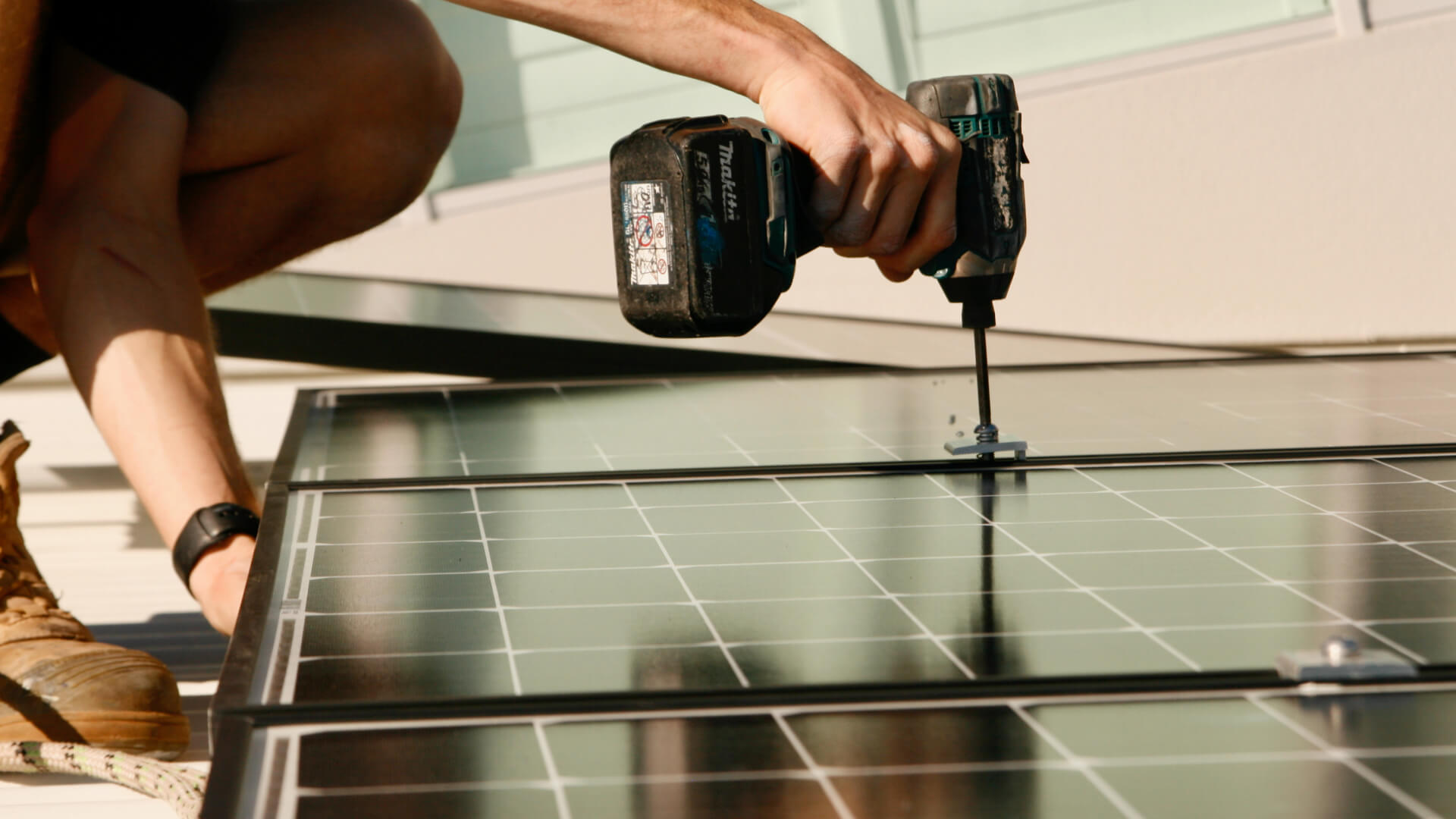 A man performing solar repairs on the Sunshine Coast using a drill on a solar panel.
