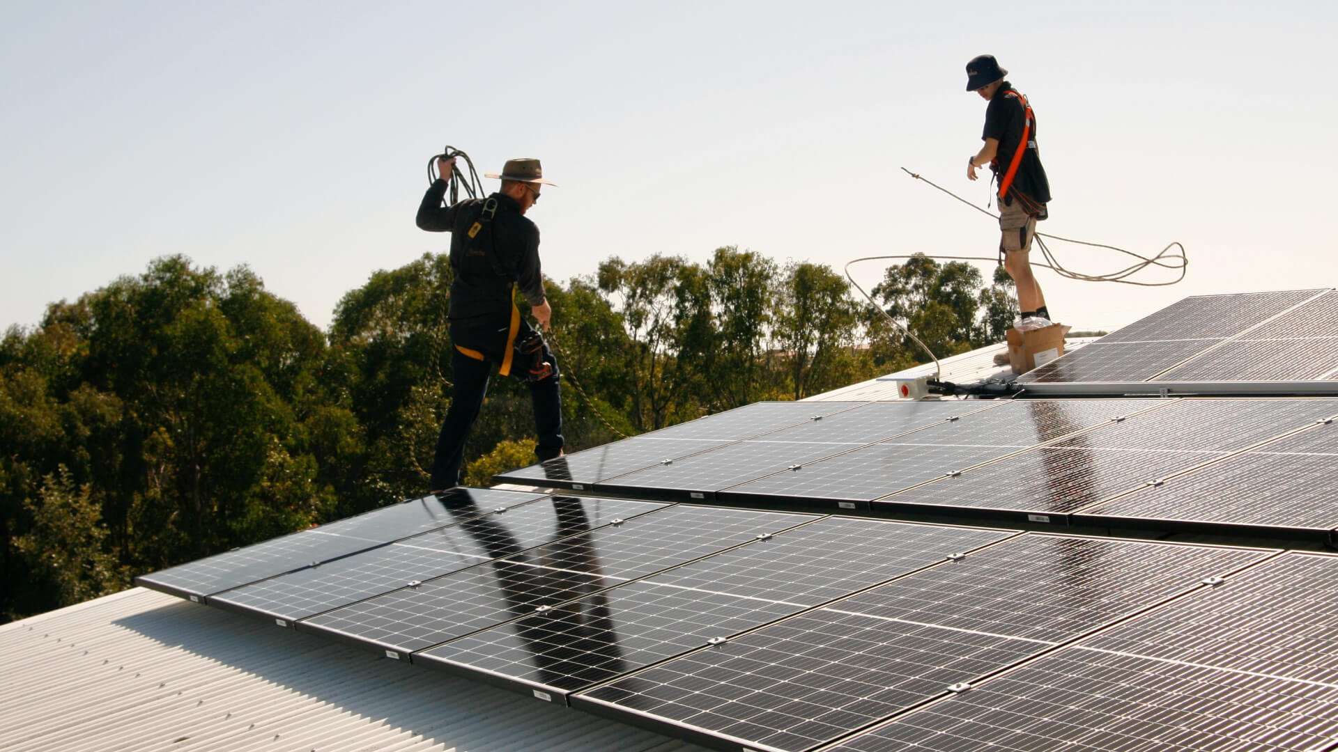 Two men working on solar panels on a rooftop on the sunshine coast.