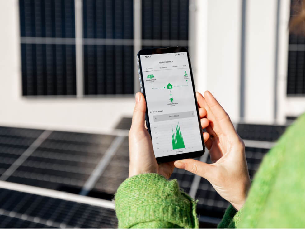 A woman holding a smart phone in front of solar panels.