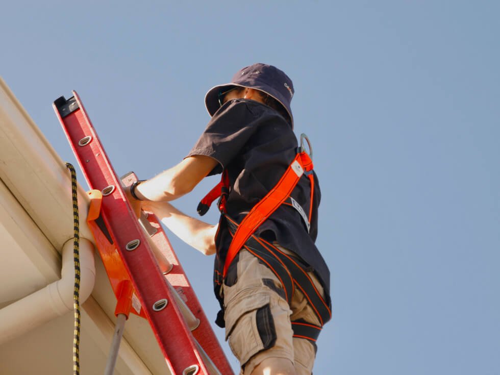 A man working on a ladder on a roof.