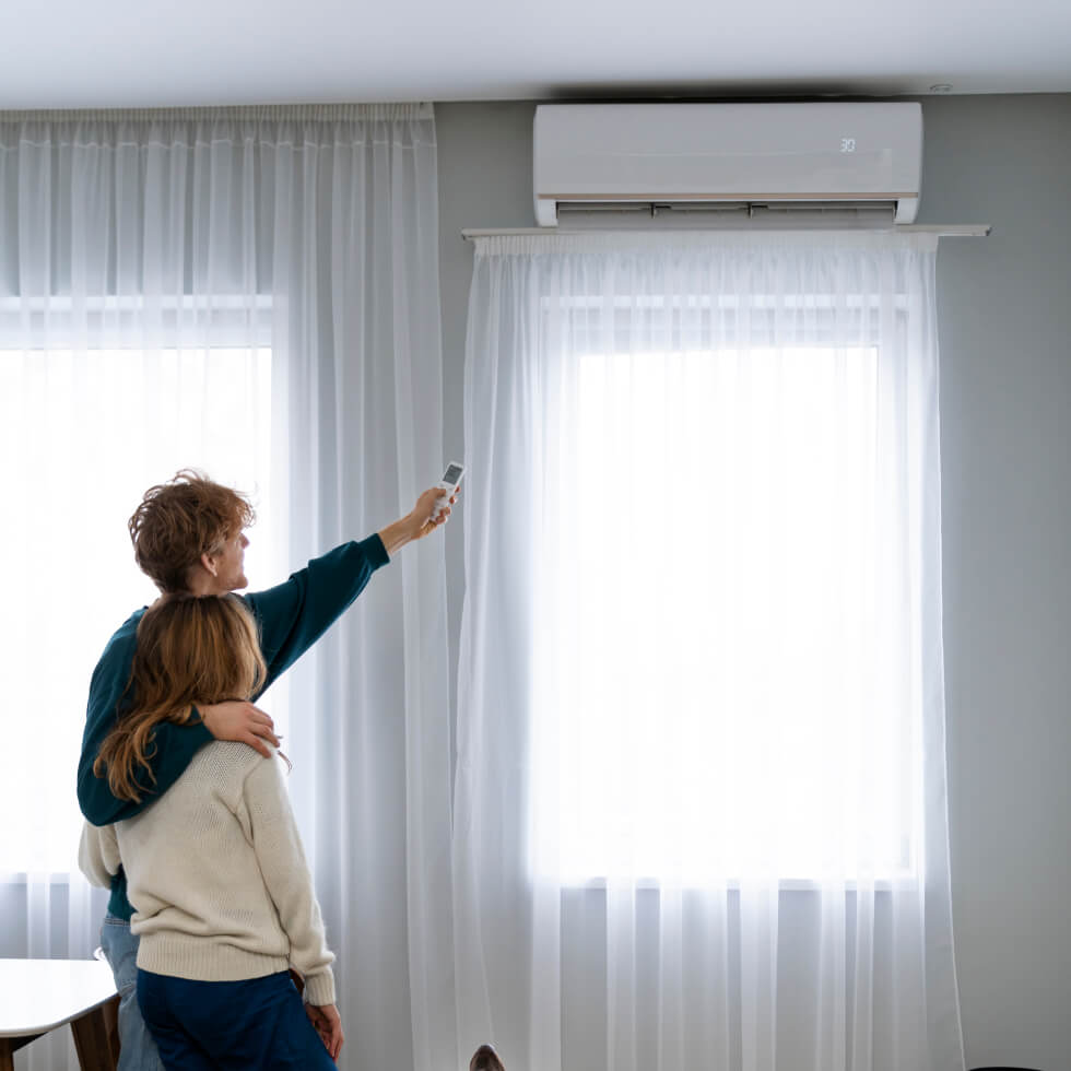 A couple examining an air conditioner in their living room on the Sunshine Coast.