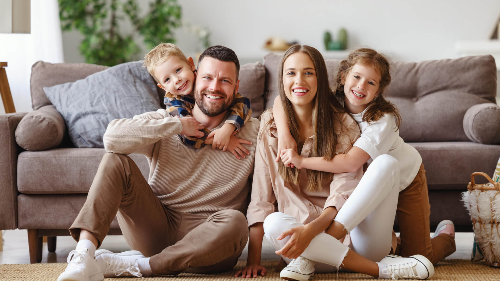 A family is sitting on the floor in front of a couch.