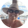 A woman wearing a hat and sunglasses at a dock.