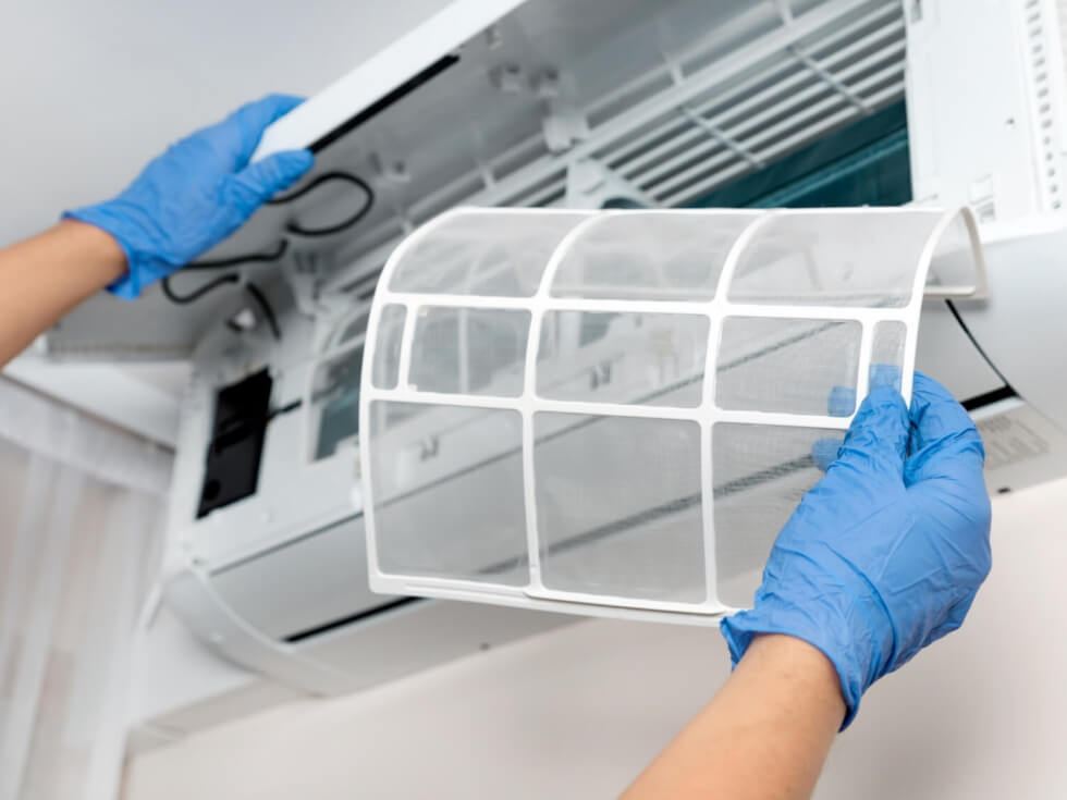 A person is removing a filter from an air conditioner.