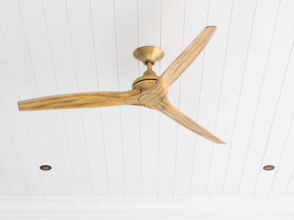 A ceiling fan with wooden blades in a white room.