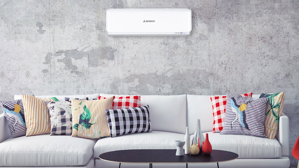 A living room with a white couch and a wall mounted air conditioner.