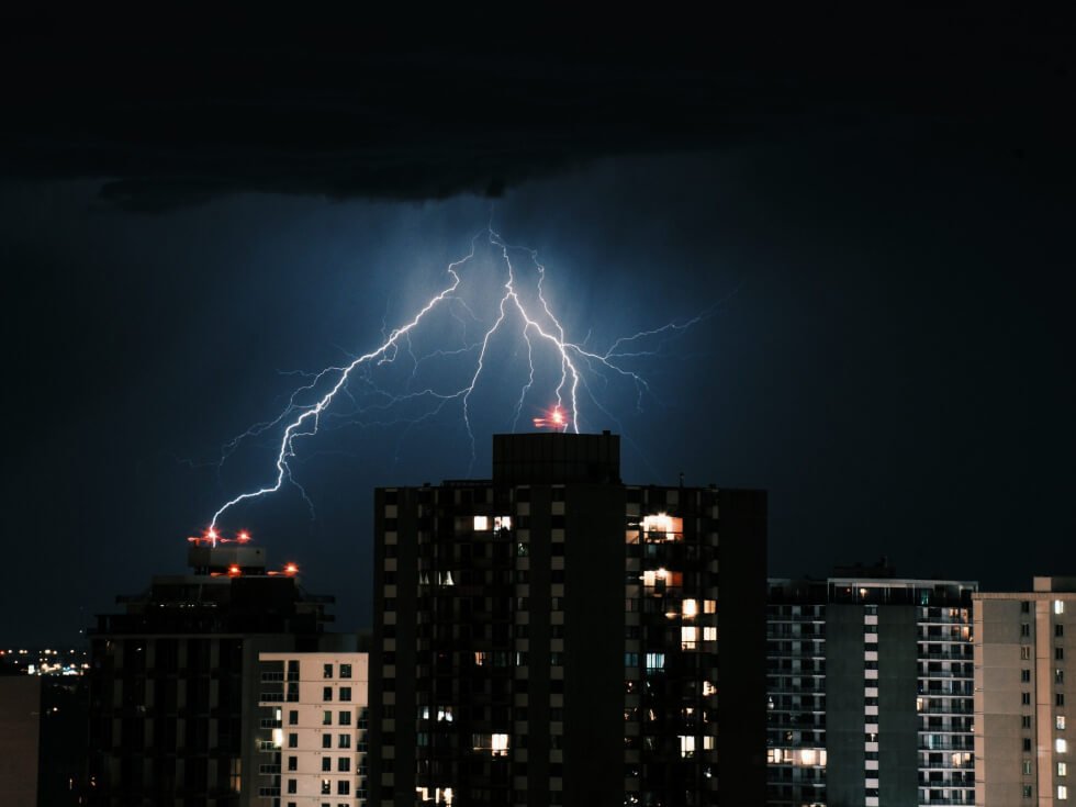 Lightning strikes over a city at night.