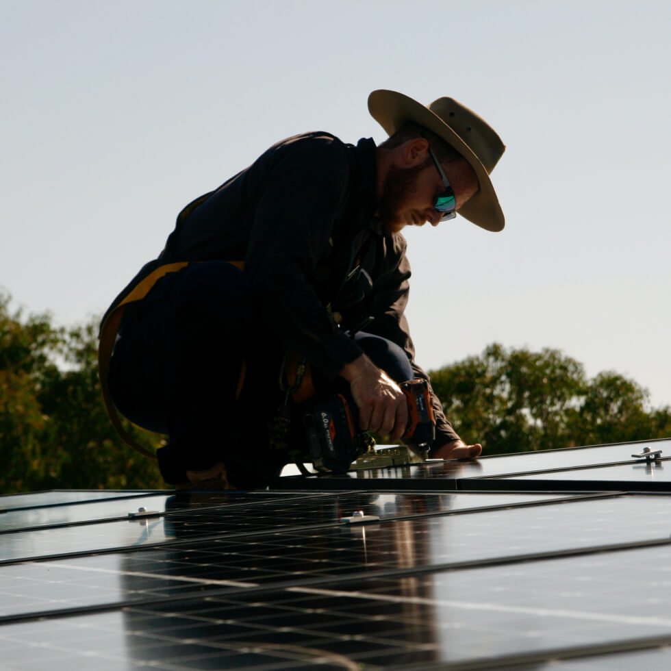 A solar installer installing on a solar panel on a roof