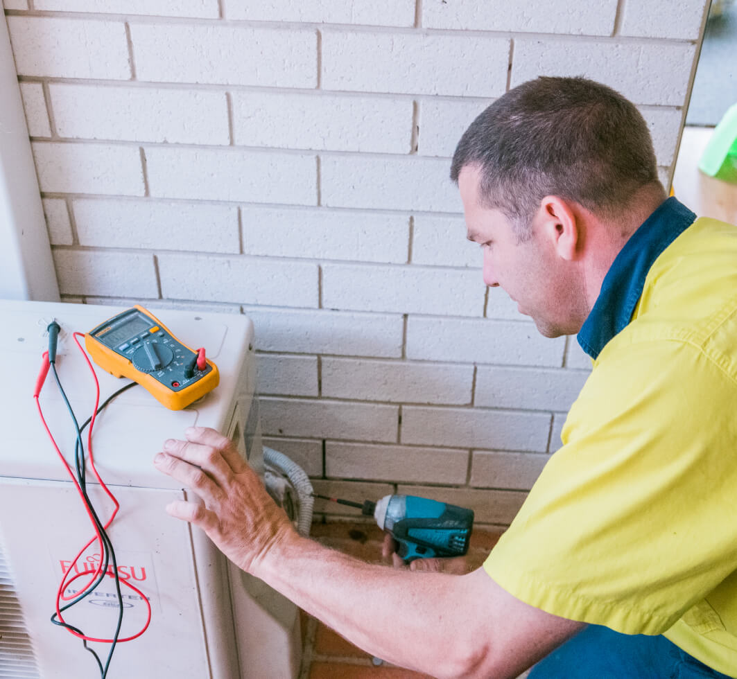 A technician is repairing a split system air conditioner on the Sunshine Coast.