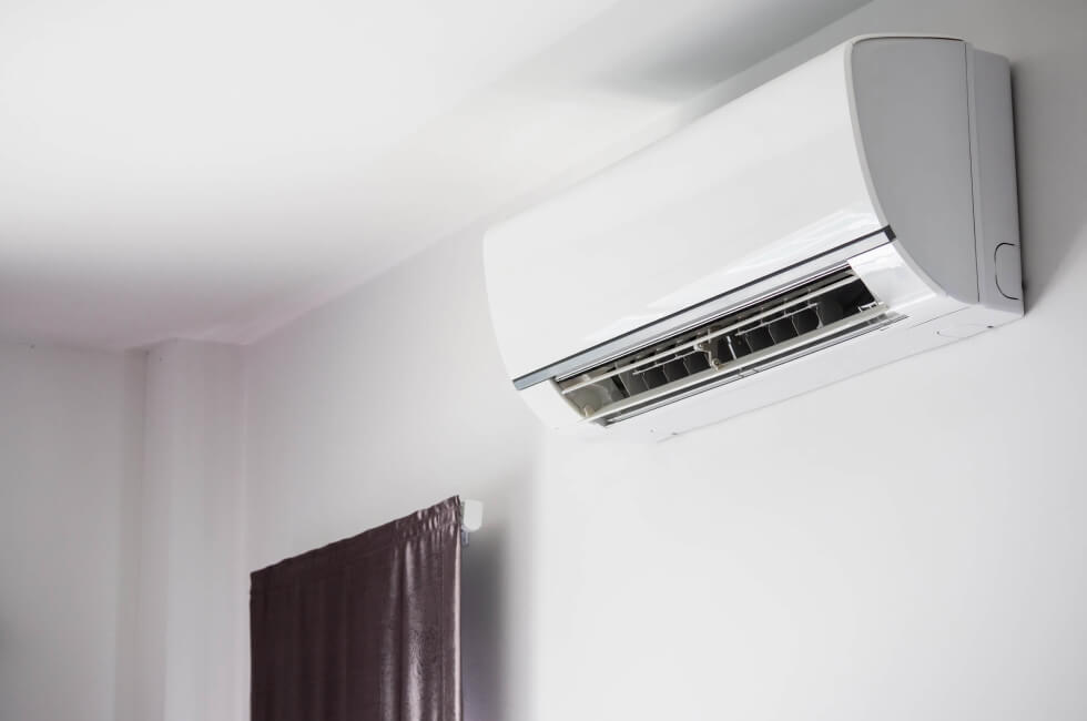 A white air conditioner hanging on the wall in a room.