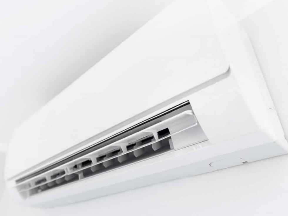 A white air conditioner on a white wall.