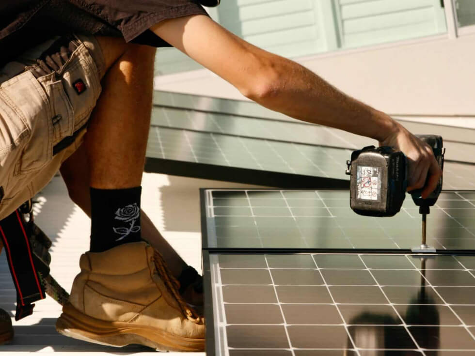 A man installing solar panels on a roof.