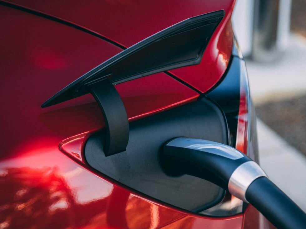 A red car is plugged into an electric charger.