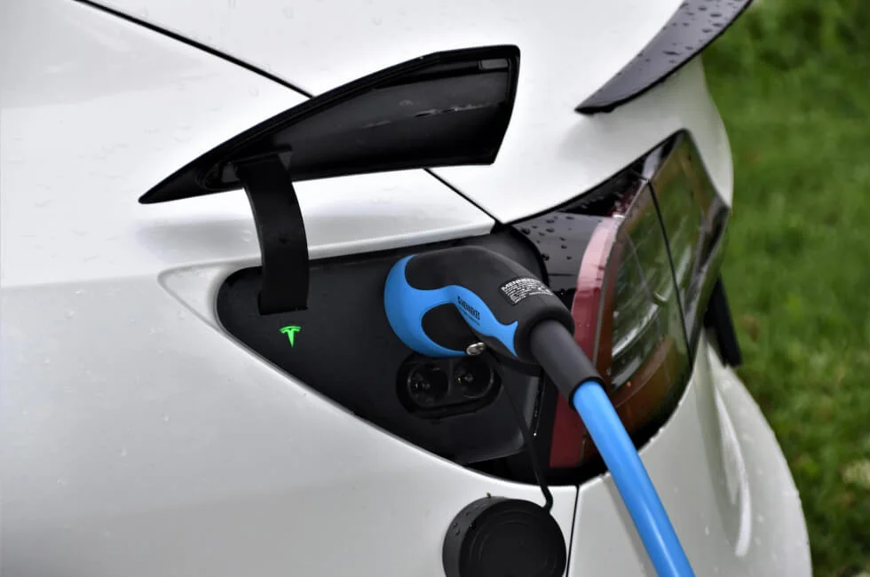 tesla home charger A white car is plugged into an electric charger.