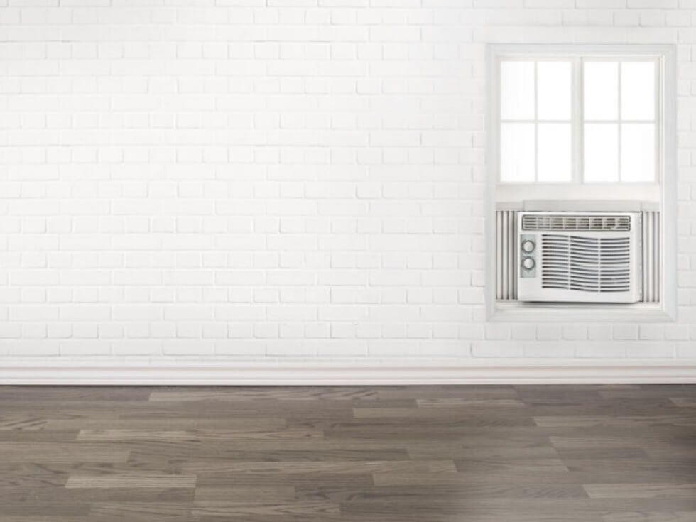 A room with a white brick wall and a white air conditioner.