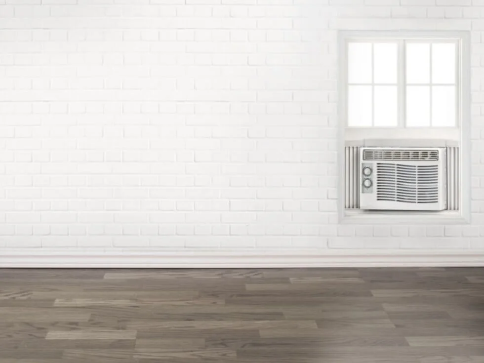 A room with a white brick wall and a white air conditioner.